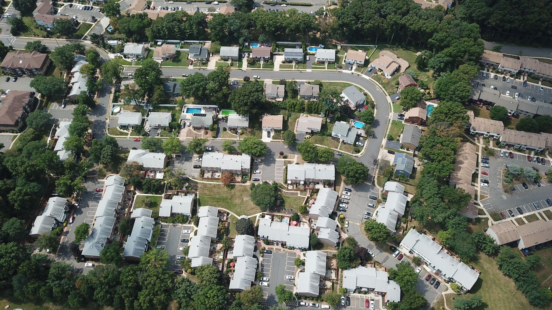 Aerial view of a suburban neighborhood with houses, trees, and winding streets.
