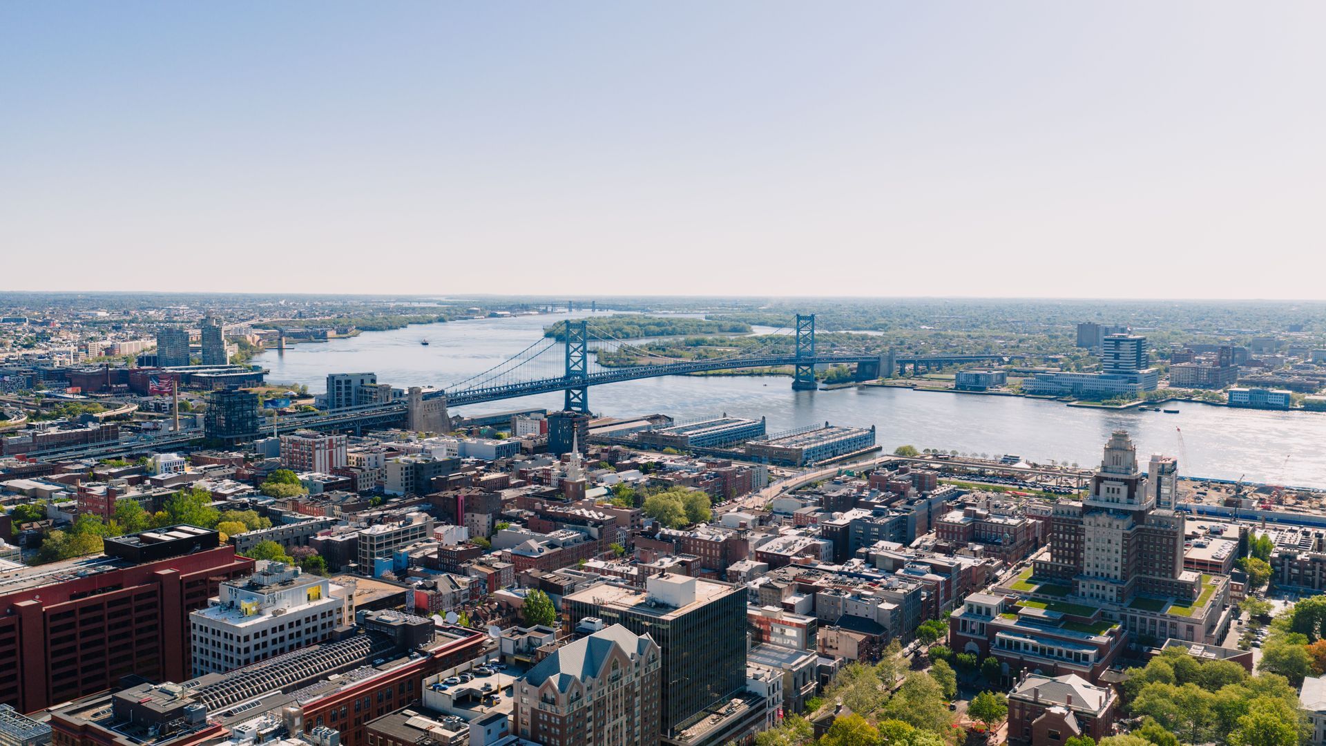 Aerial view of a city skyline with a river and bridge under a clear sky