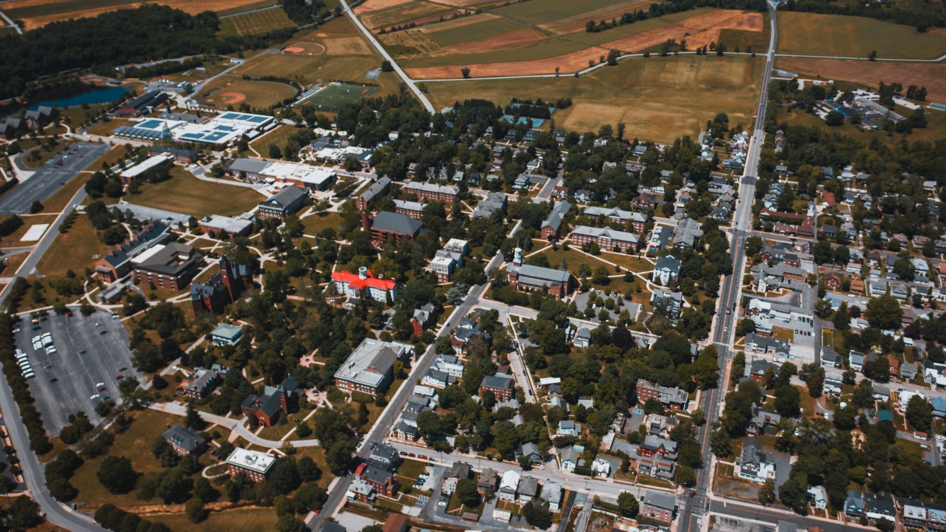 Aerial view of a small town with houses, streets, and surrounding fields at sunset