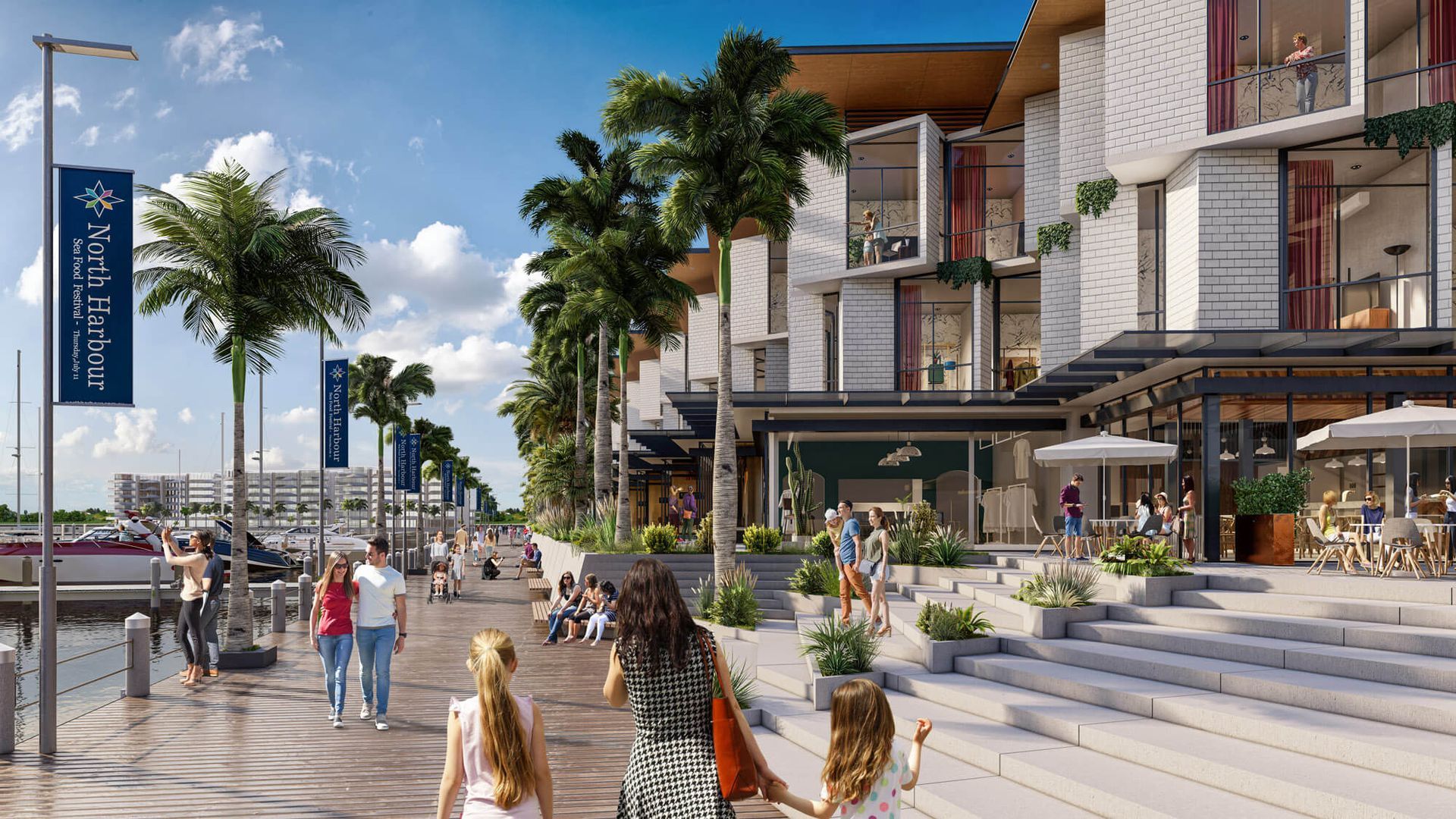Sunny seaside promenade with palm trees, shops, and people walking beside modern buildings.