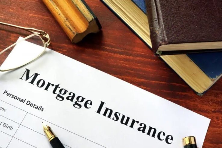 Mortgage insurance form with pen, glasses, and books on a wooden desk.