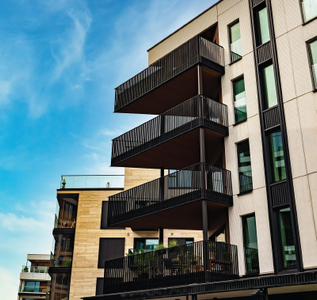 Modern apartment building with stacked black balconies against a blue sky