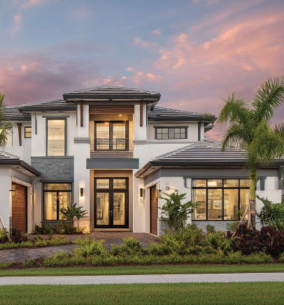 Modern two-story house with large windows and palm trees at sunset