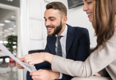 Two coworkers smiling and reviewing a document in a bright office