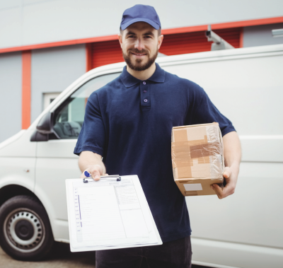 Courier in blue uniform holding a clipboard and package beside a white delivery van