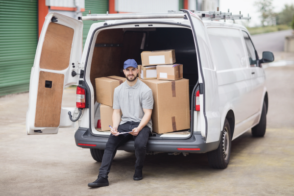 Mover sitting in the back of a white cargo van loaded with boxes and furniture