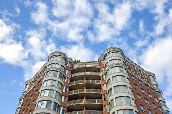 Low-angle view of a modern high-rise building with rounded balconies against a blue sky with clouds