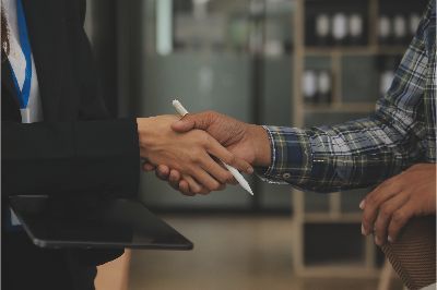 Hands exchanging a pen during a business handshake in an office setting