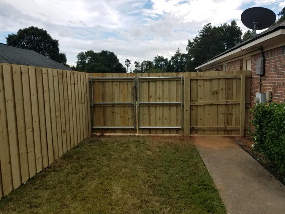 A wooden fence with a gate in the backyard of a house.
