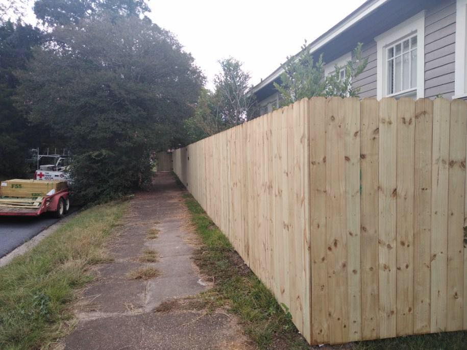 A wooden fence along a sidewalk next to a house