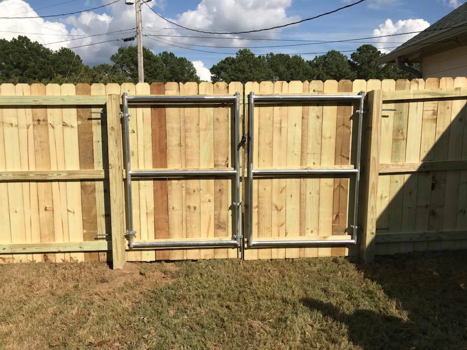 A wooden fence with a metal gate in the backyard