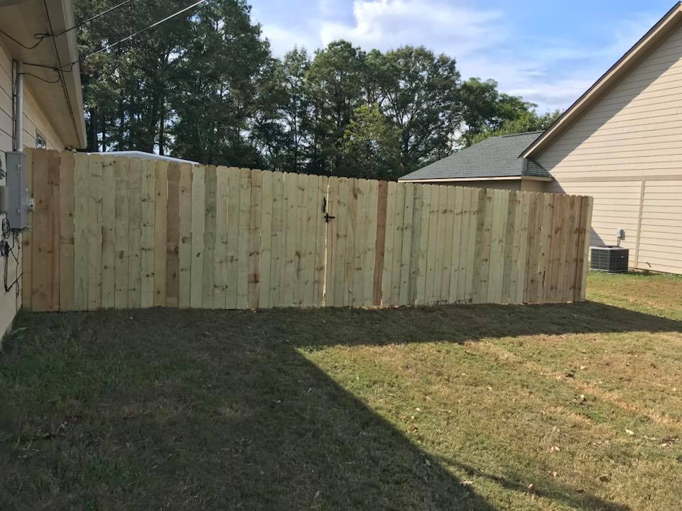 A wooden fence is in the backyard of a house.