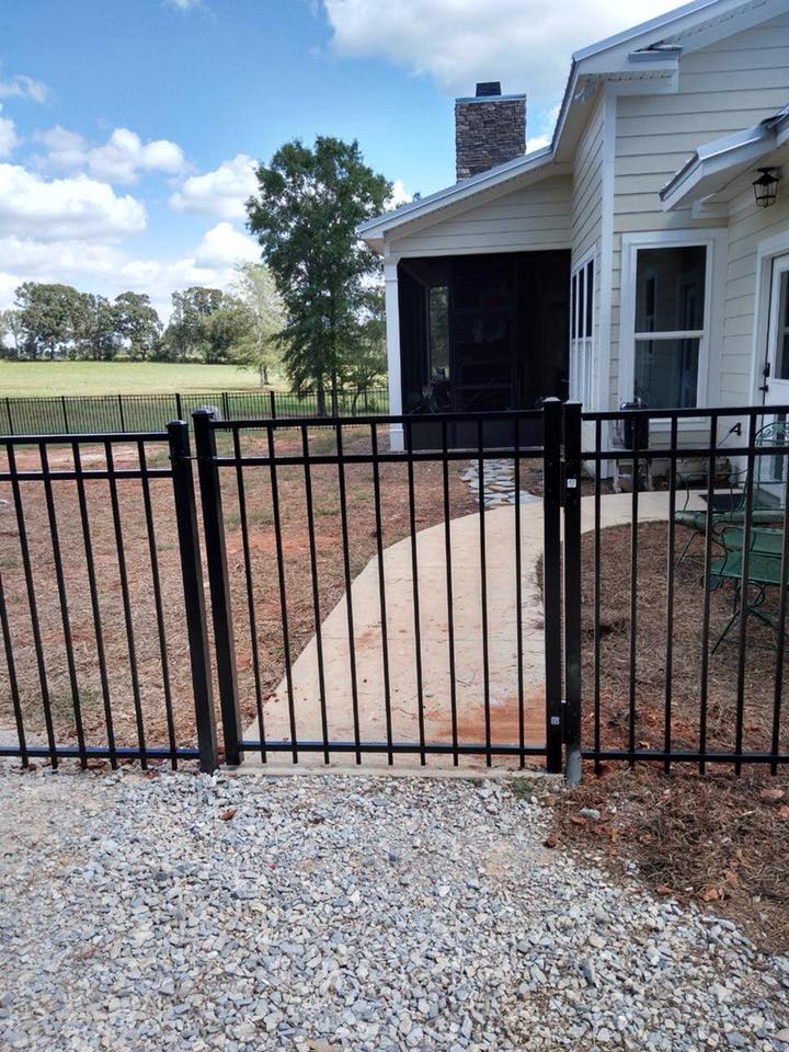 A black fence with a gate in front of a house.