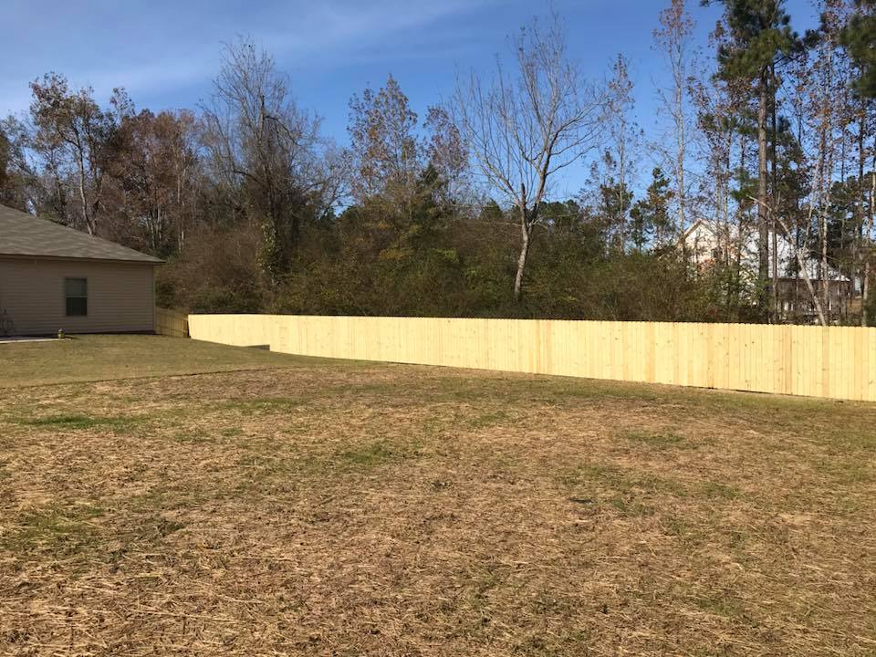 There is a wooden fence in Columbus Ga in the middle of a grassy field.