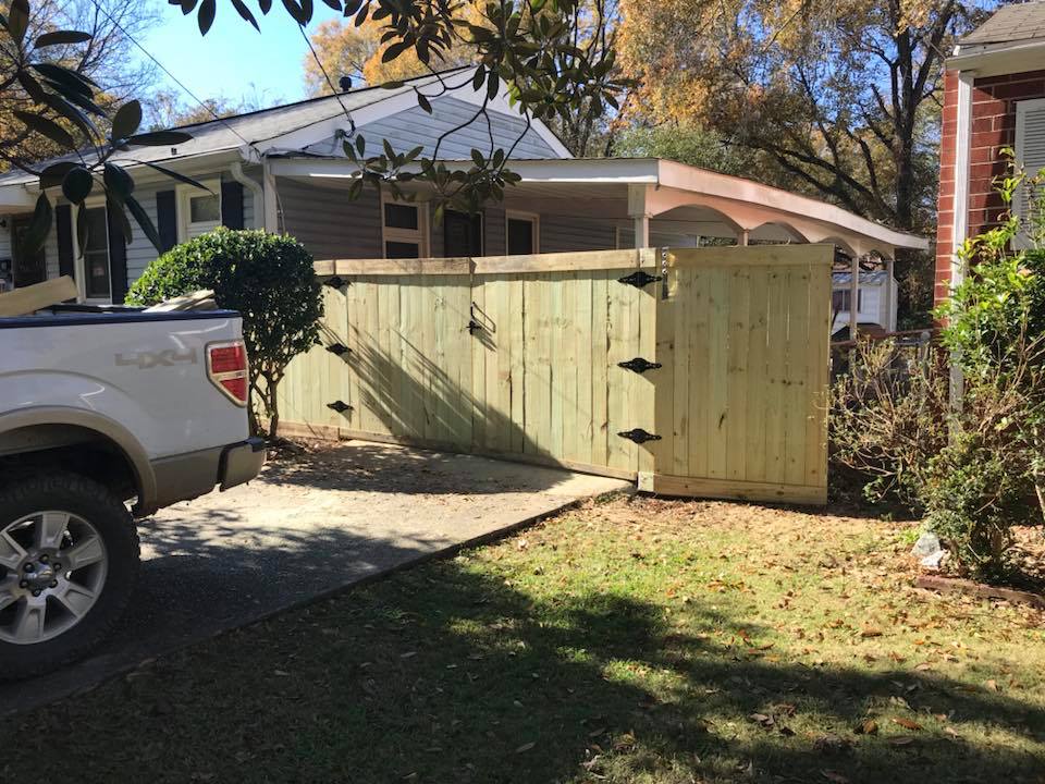 A white truck is parked in front of a house next to a wooden fence in Columbus ga.