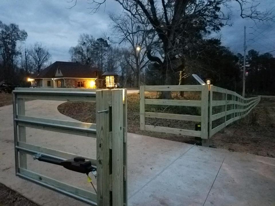 A wooden fence in Columbus ga surrounds a driveway with a house in the background