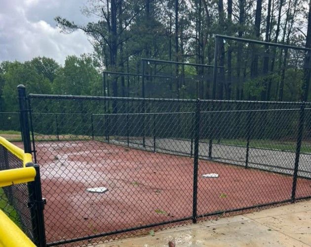 A black chain link fence surrounds a baseball field