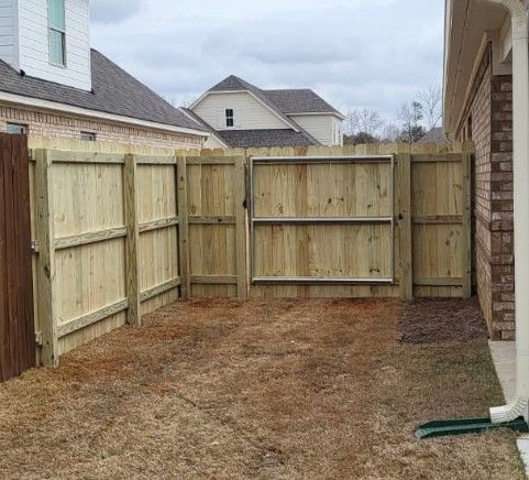 A wooden fence with a gate in the backyard of a house.