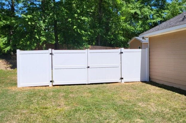 A white fence is in the backyard of a house.
