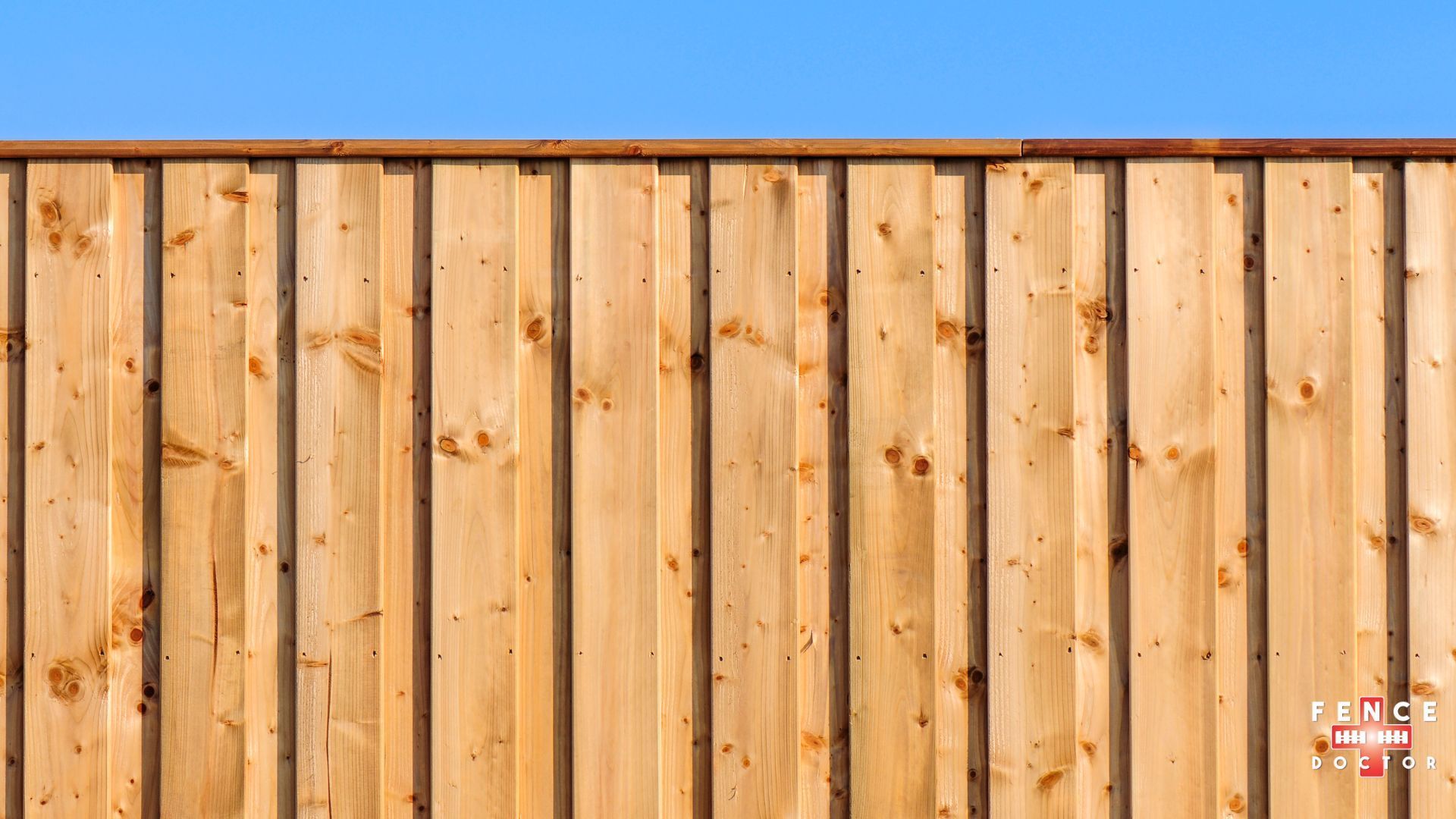 A wooden fence with a blue sky in the background.