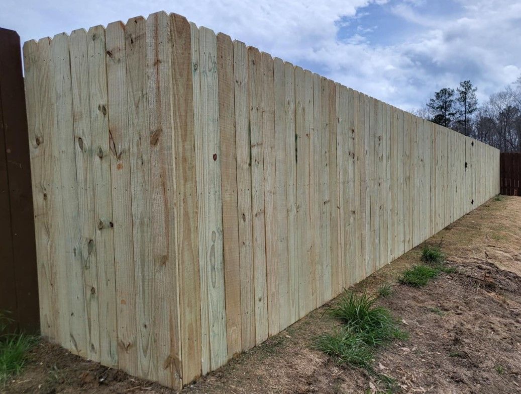 A long wooden fence is sitting on top of a dirt field.