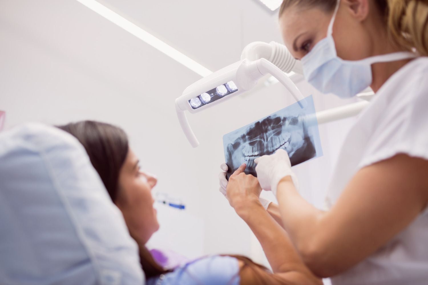 Un dentista esamina i denti di un paziente con una radiografia dentale in una clinica luminosa