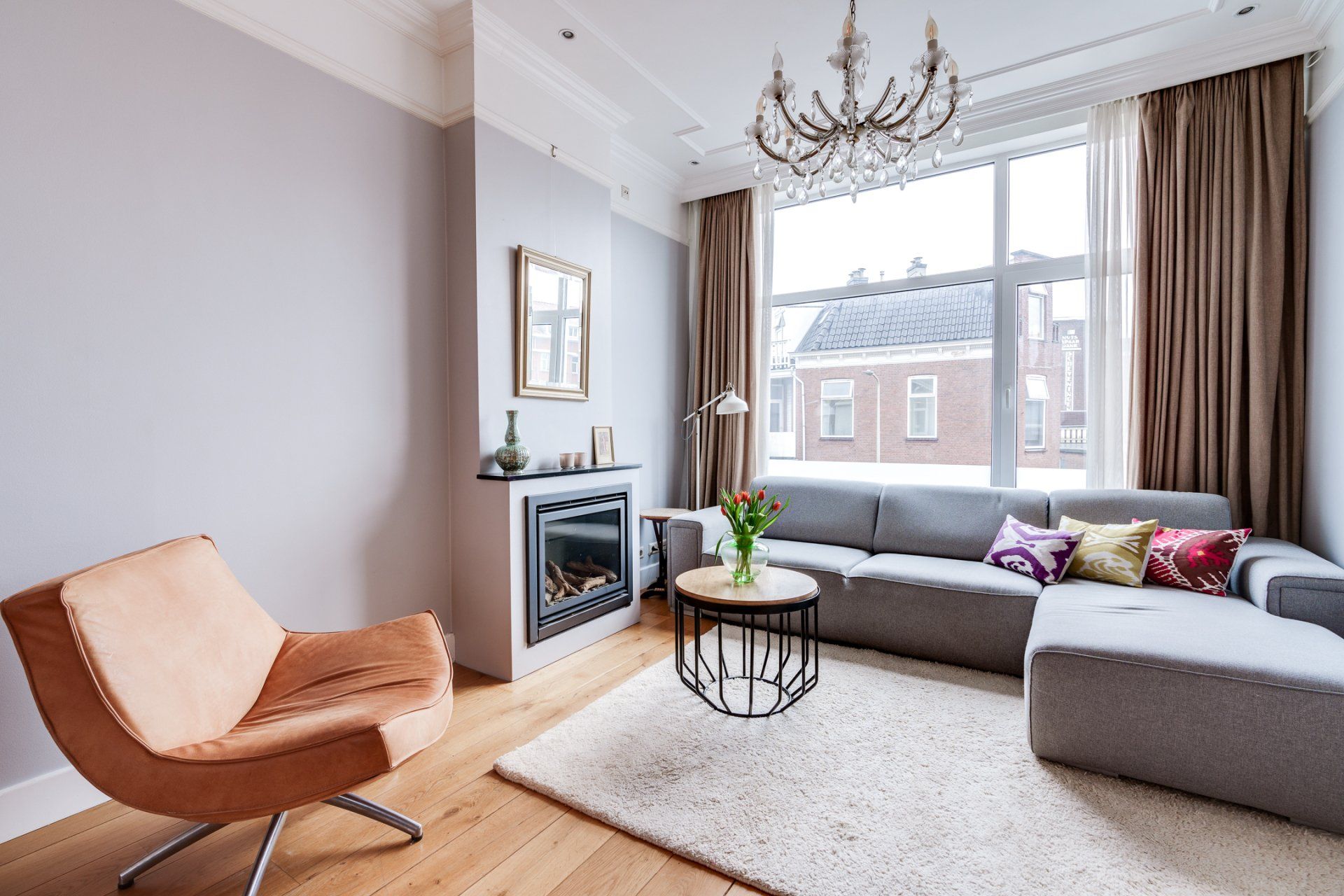 Een woonkamer met een bank, stoel, tafel en open haard.