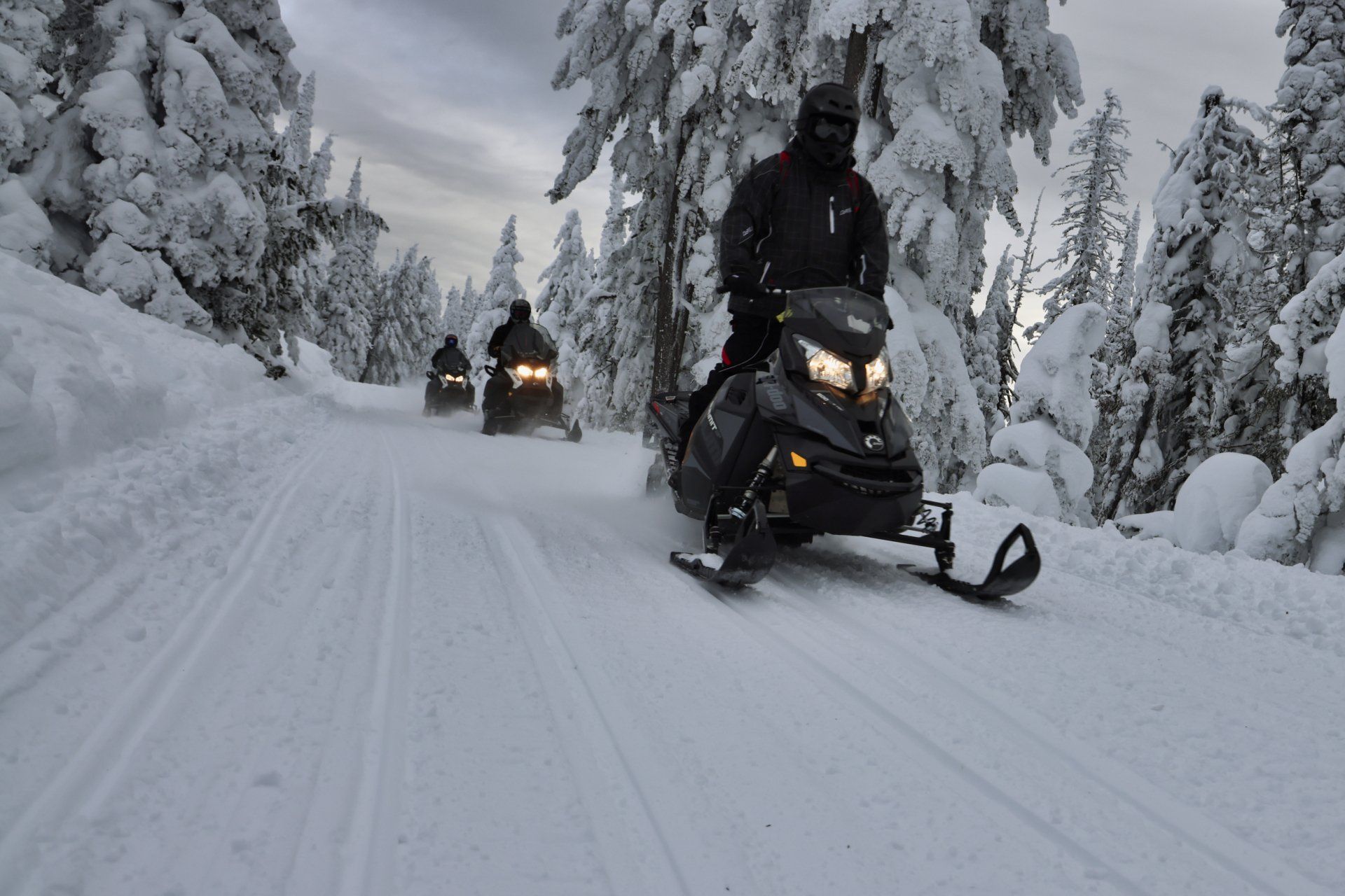 3 snowmobiles going down snowy hill