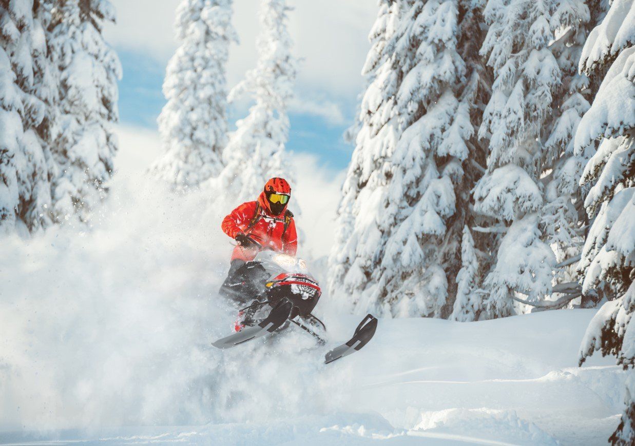 person in red suit riding snow mobile