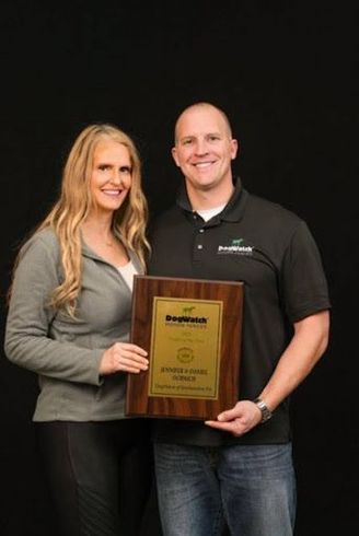 A man and a woman are standing next to each other holding a plaque.