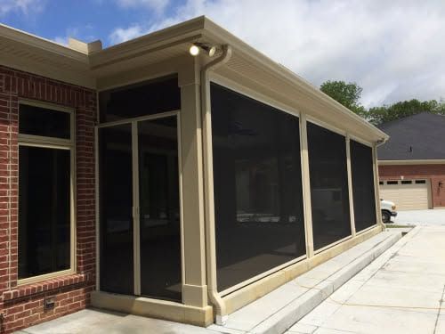 Screened porch with tan trim on a brick house beside a driveway