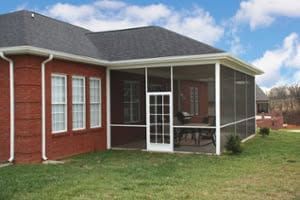 Brick house with screened porch and white columns on a grassy yard