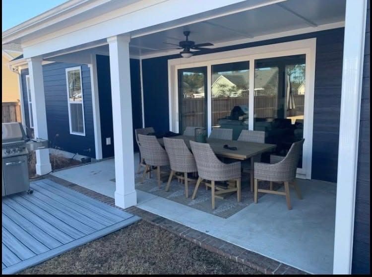Covered patio with outdoor dining table and chairs beside a blue house