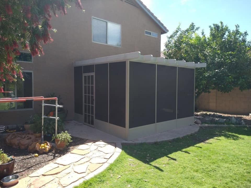 Backyard patio with a small screened enclosure beside a house, stone path, and green lawn