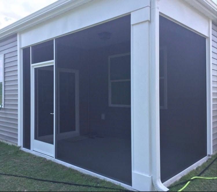 Screened porch with white trim and dark mesh panels on a grassy backyard patio