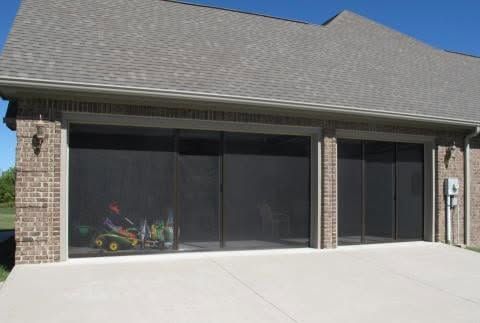 Brick house patio with large screened windows and a gray shingled roof