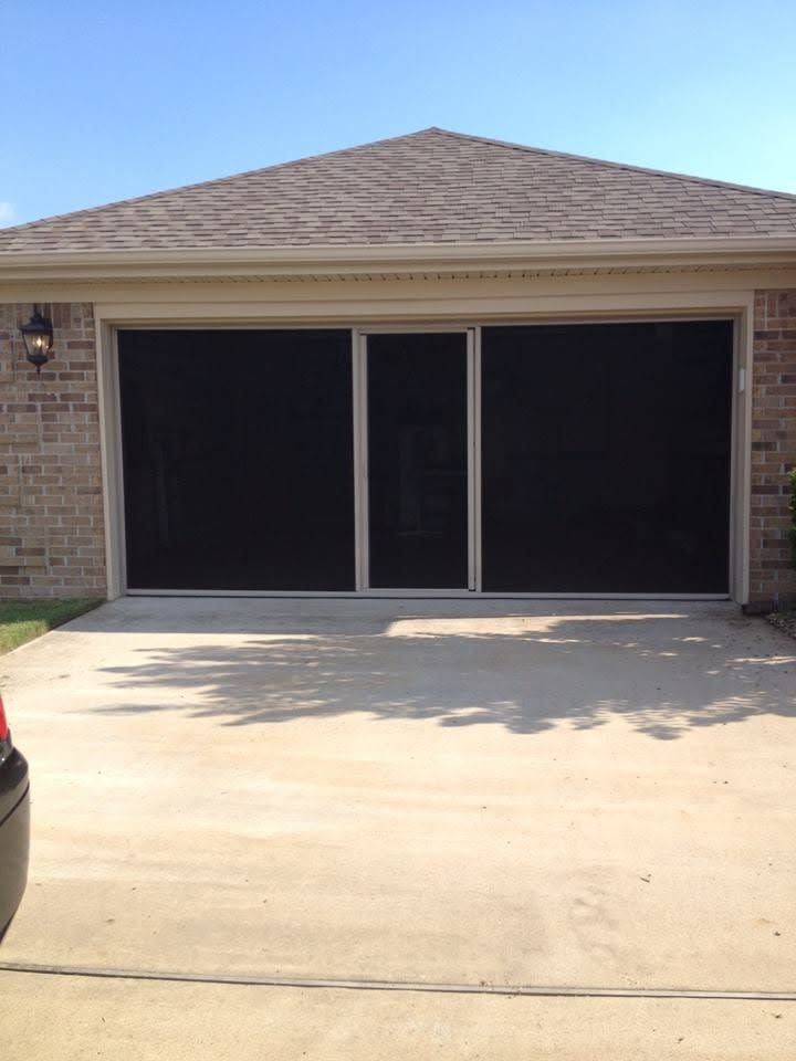 Closed double garage doors on a brick house with a sunlit driveway.