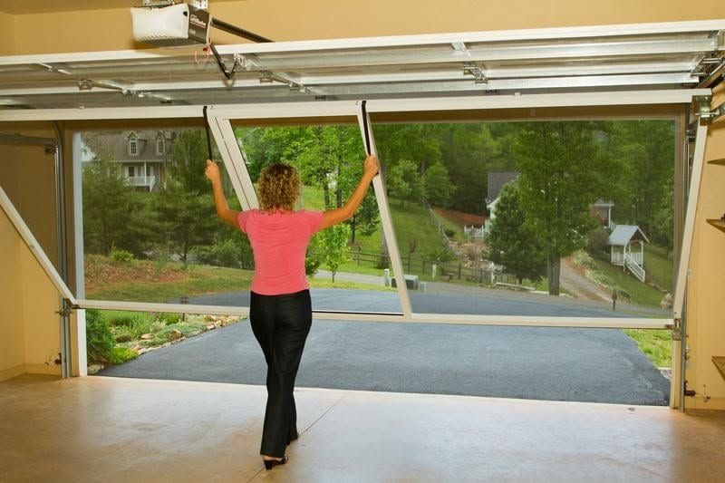 Person in pink top raising garage door inside a driveway.