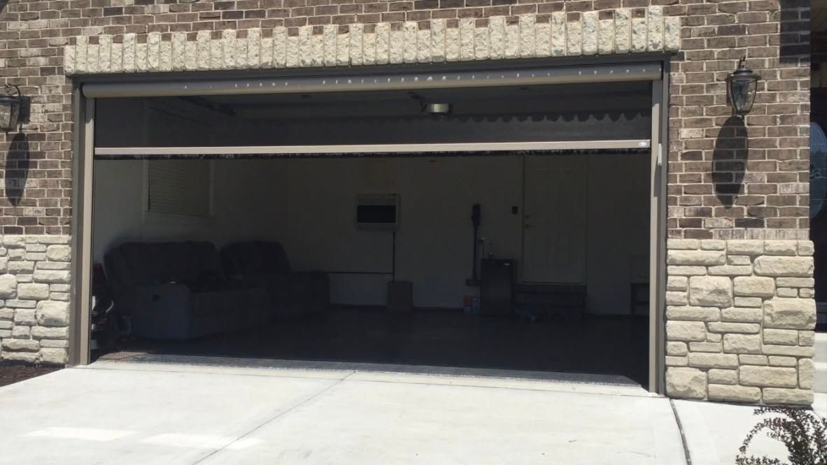 Open two-car garage on a brick house, with a concrete driveway and dim interior.