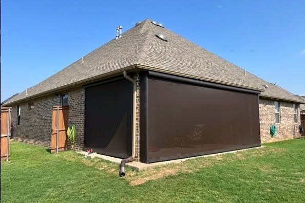 House exterior with tan roof and brown screened patio enclosure on a grassy lawn
