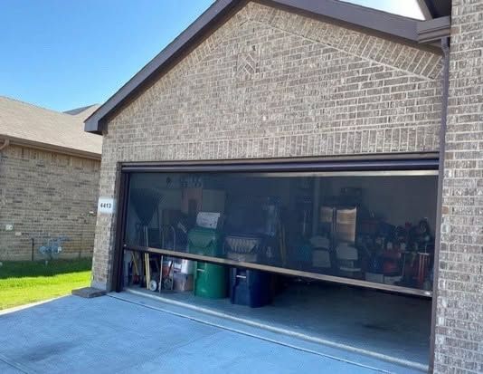 Brick house with a partially open garage door, revealing stored items inside.