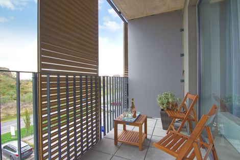 Balcony with two wooden chairs, small table, potted plants, and city view through a slatted screen