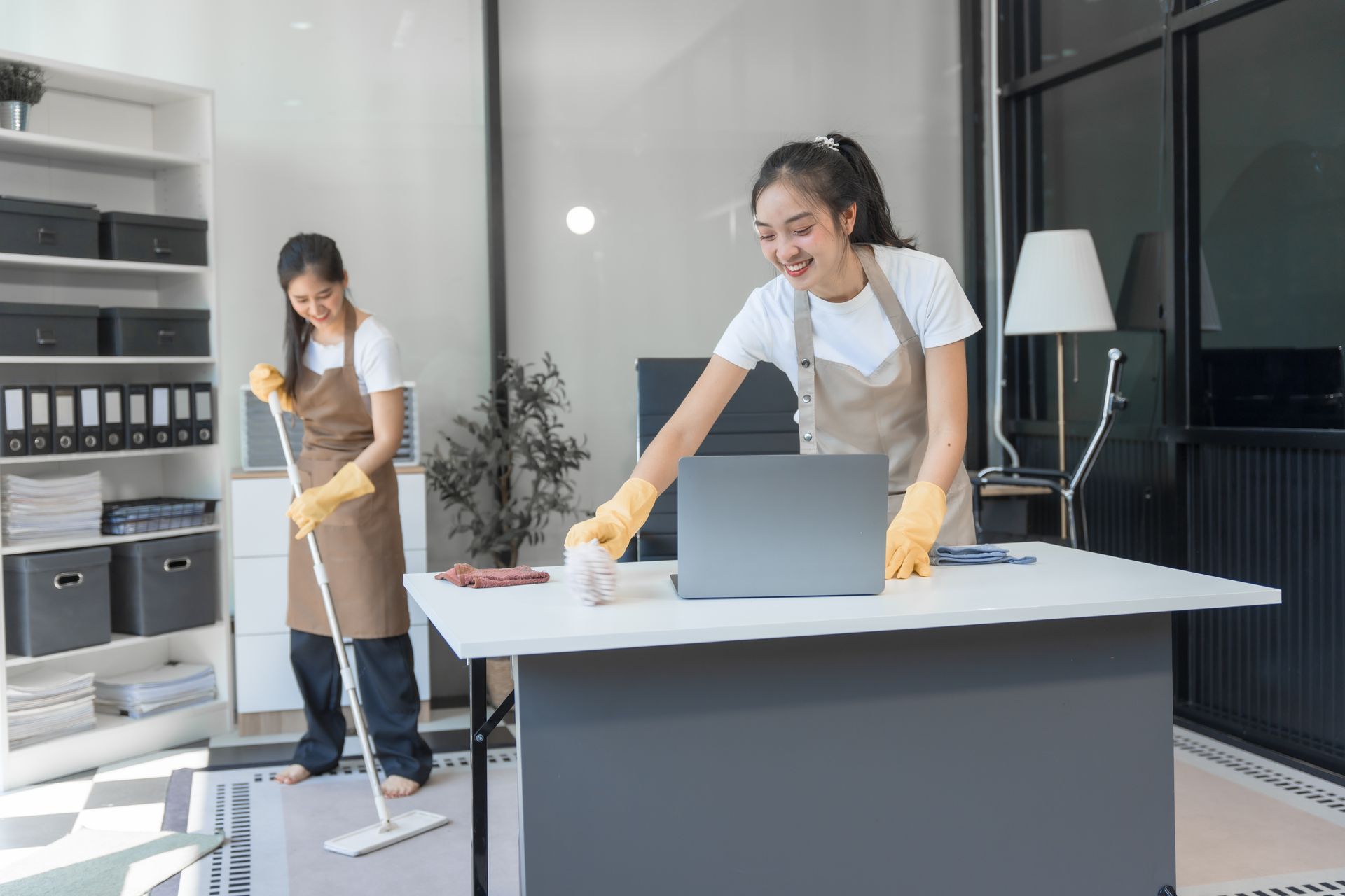 Two women are cleaning a desk in an office.