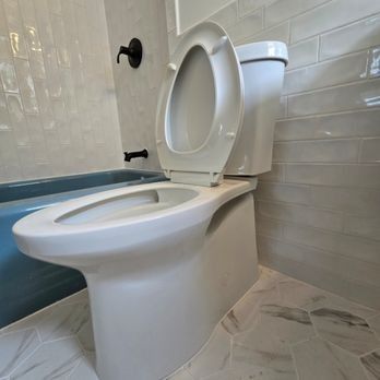 Toilet in a bathroom with the seat up; a bathtub is visible to the left.