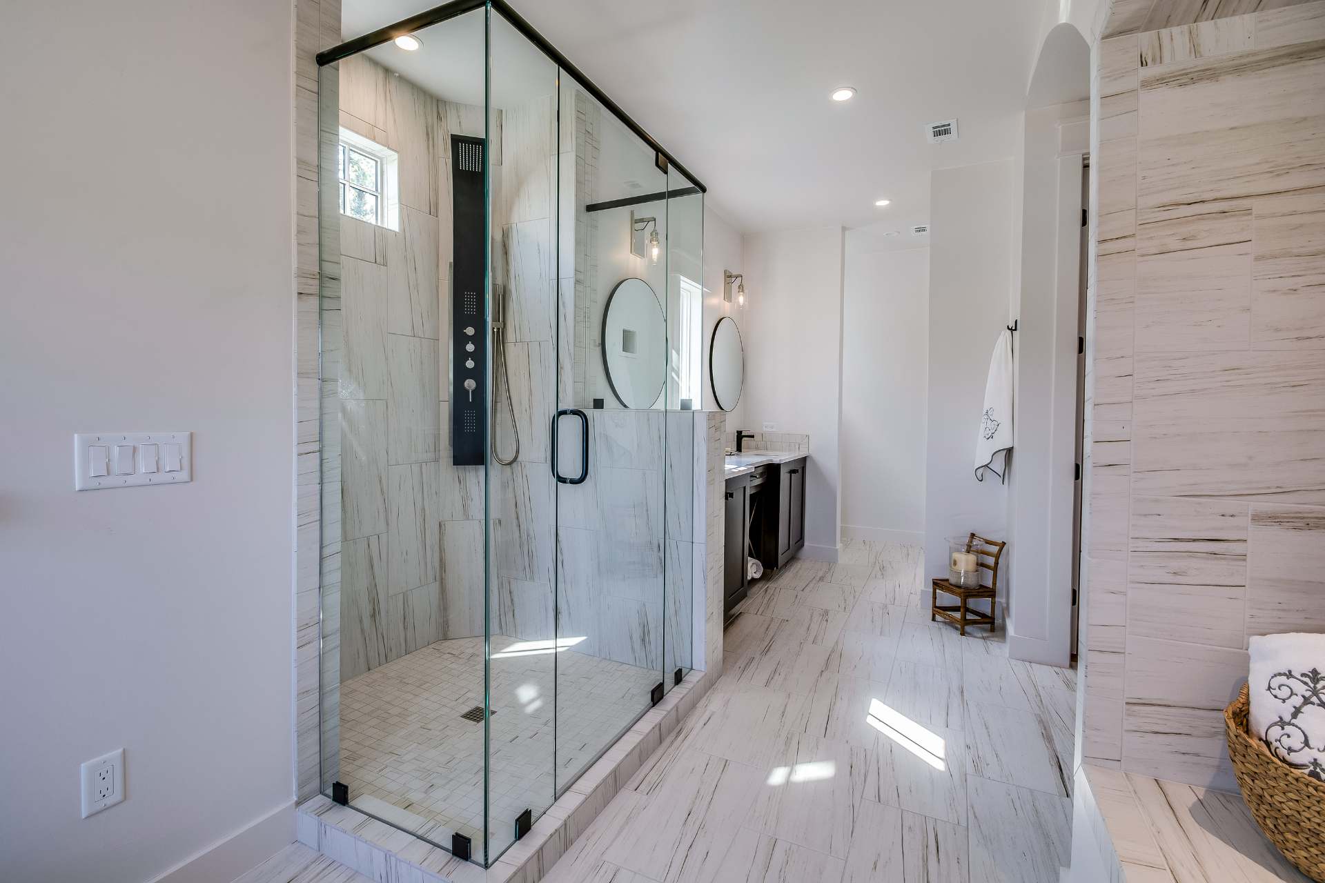Bright modern bathroom with glass shower, freestanding tub, and white marble finishes