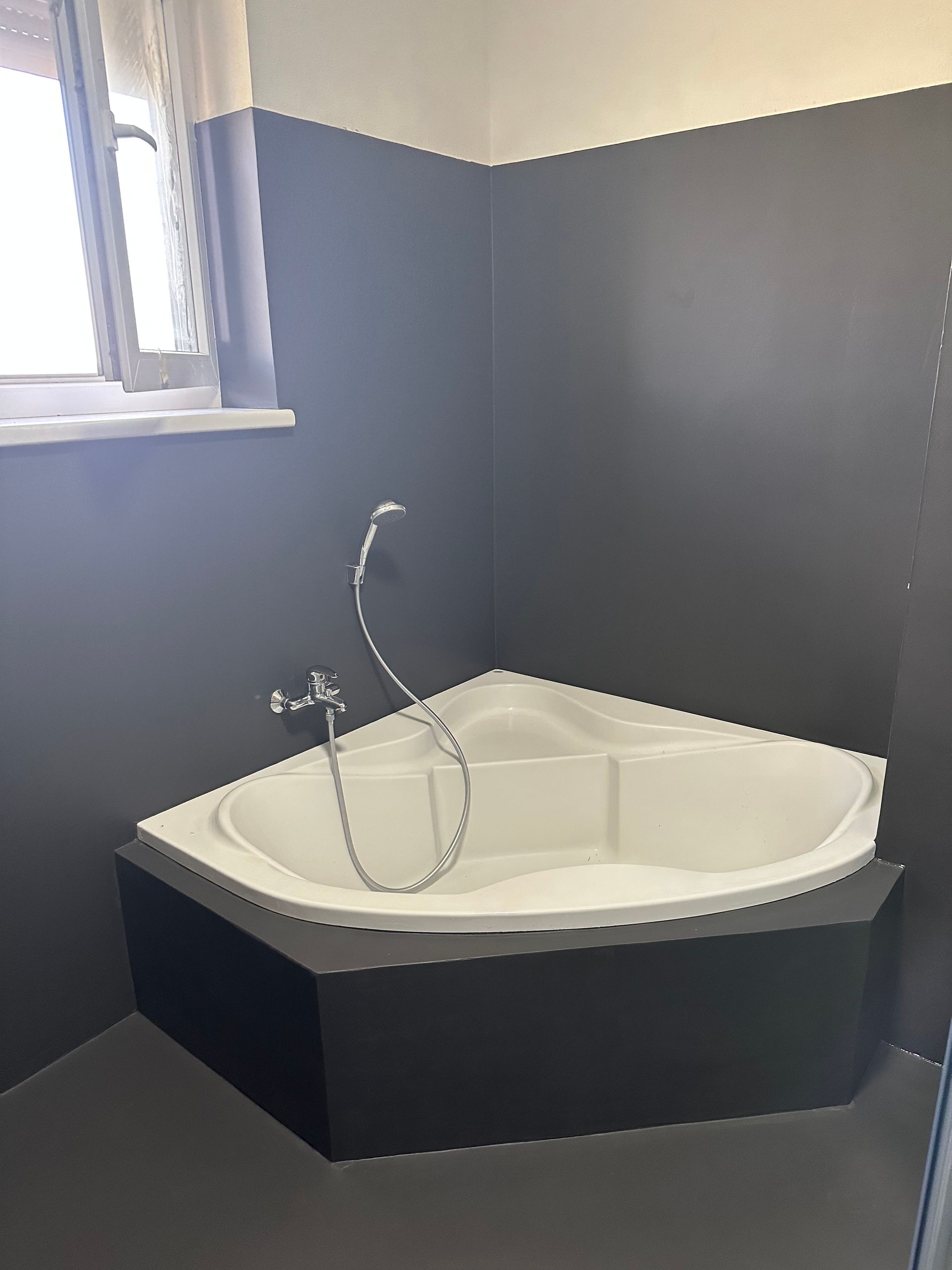 Ein Badezimmer mit Eckbadewanne und Duschkopf.