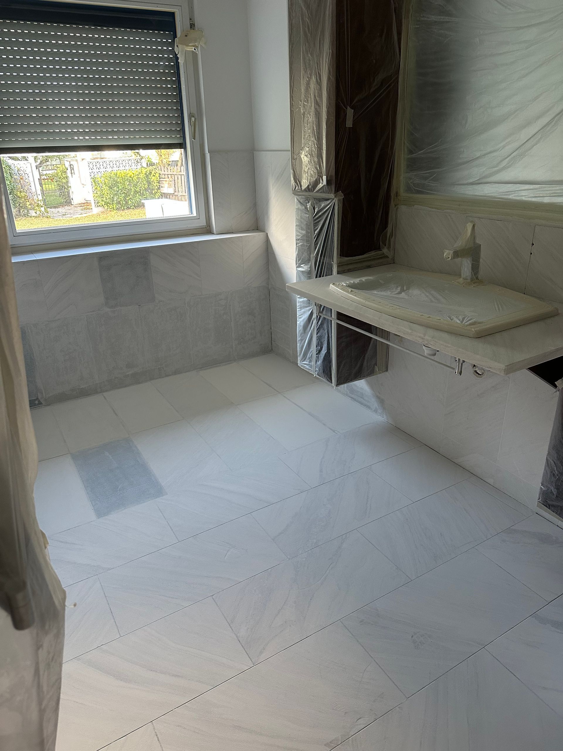 Ein Badezimmer mit Waschbecken, Spiegel und Fenster.