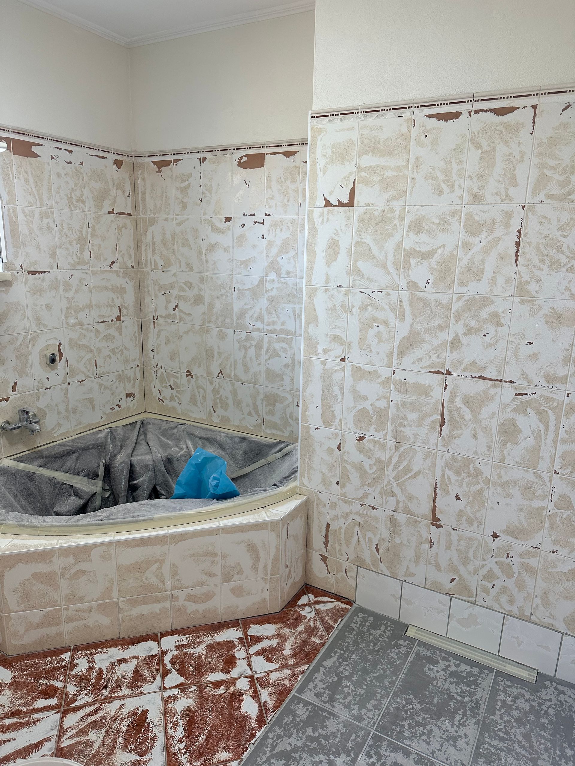 Ein Badezimmer mit Badewanne und entfernten Fliesen.