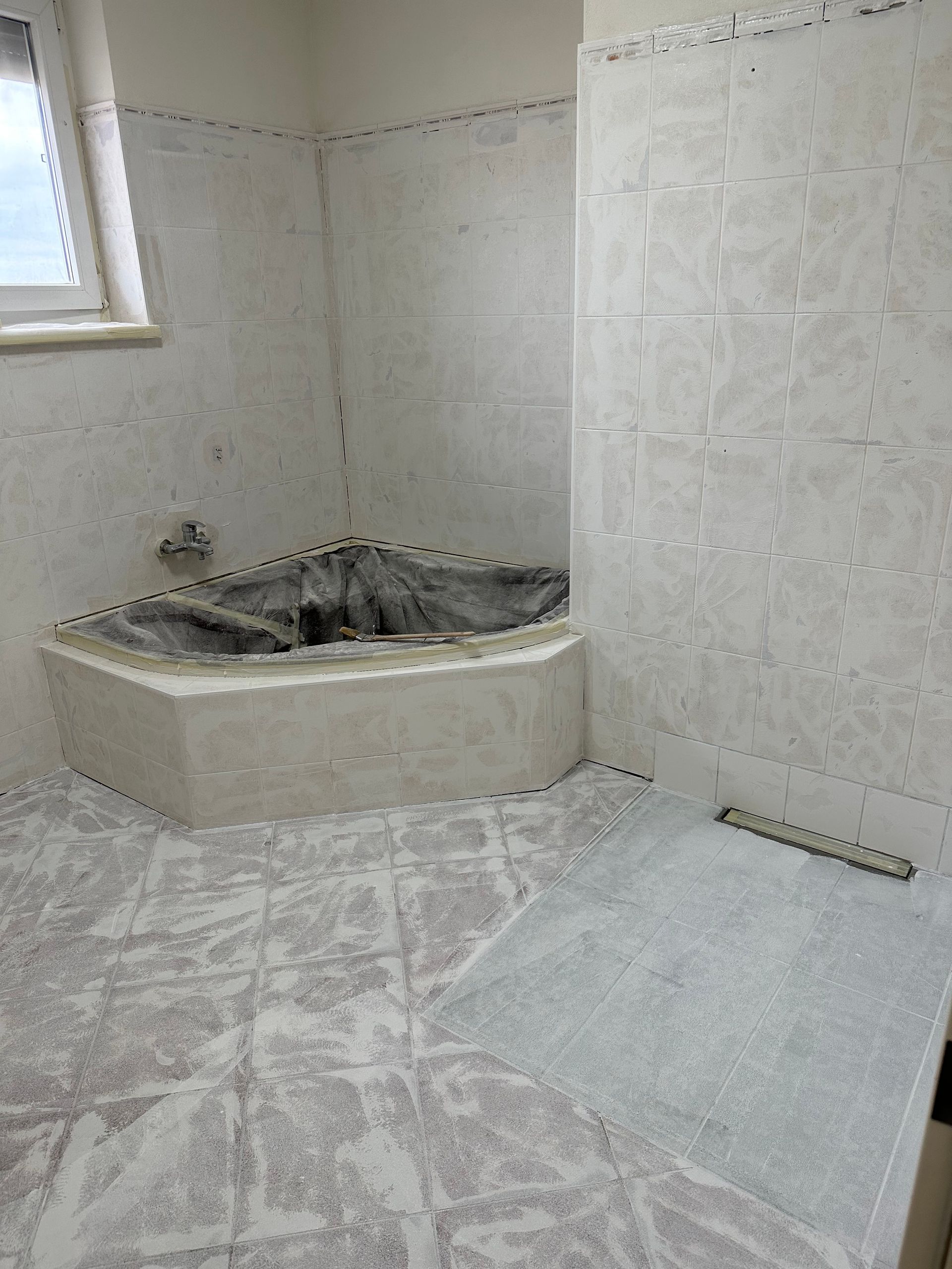 Ein Badezimmer mit Eckbadewanne und Fenster.
