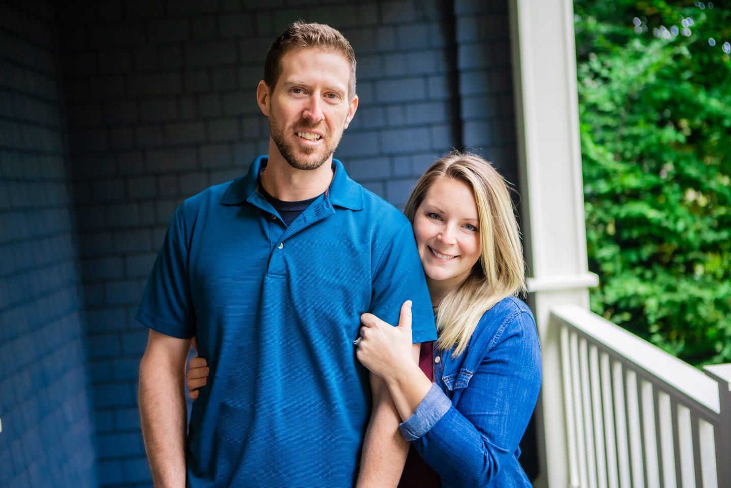 a man and woman are posing for a picture on a porch